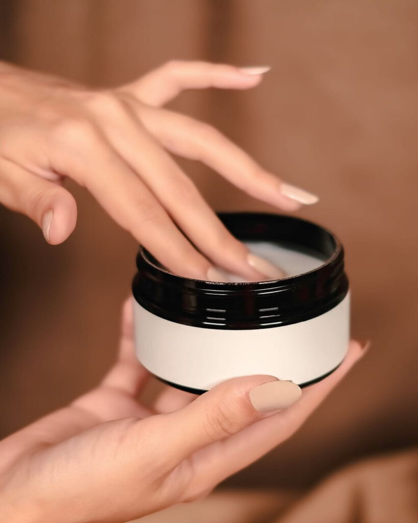Hands holding an open jar of cleansing balm